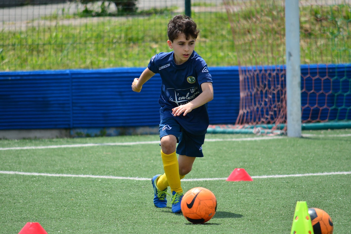 Bambino della scuola calcio Vibe Ronchese con divisa ufficiale durante un esercizio di guida della palla